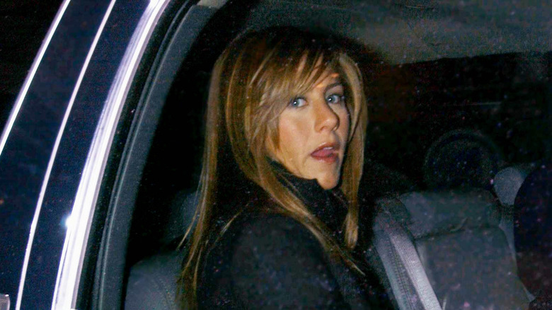 Jennifer Aniston in a limo wearing a black jacket in a paparazzi photo