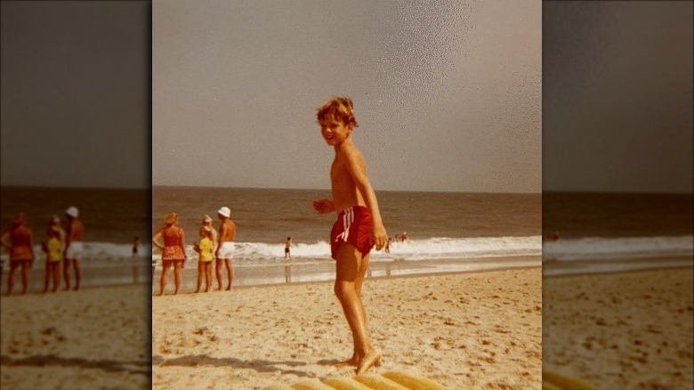 Jason Heigl wearing red shorts on a beach.