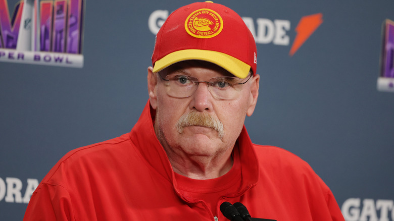 Andy Reid wearing Chiefs hat in front of microphones