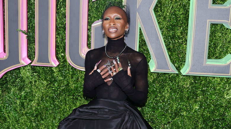 Cynthia Erivo wearing a black dress and placing her hands on her heart at a "Wicked" screening.