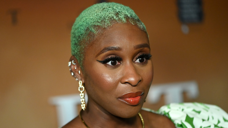 Cynthia Erivo with green hair speaking to reporters on the red carpet.