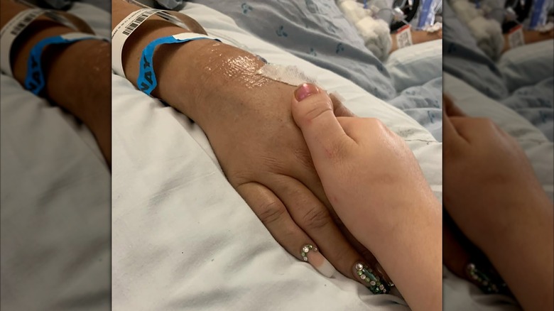 Bonnie Chapman holding Beth Chapman's hand in the hospital