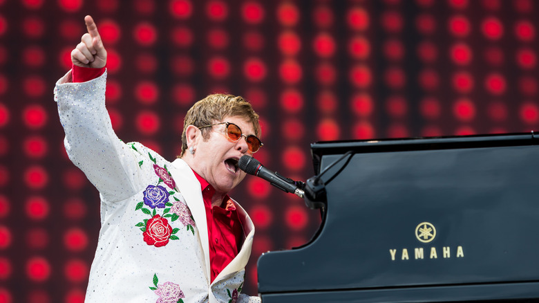 Elton John performing on stage and pointing