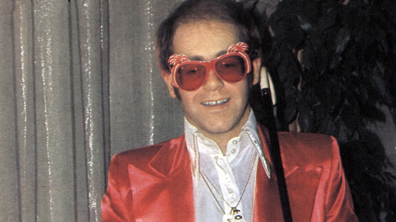 Elton John posing with a cane