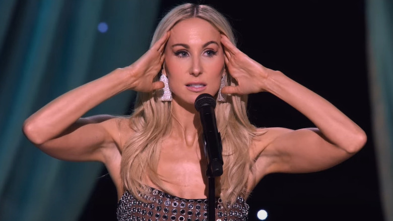 Nikki Glaser with hands on side of head