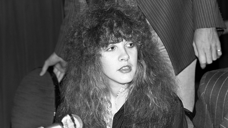 Stevie Nicks wearing a black sweater with teased dark hair