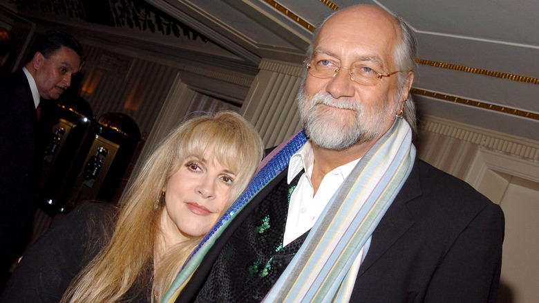 Stevie Nicks in a black jacket and Mick Fleetwood in a black jacket and colorful scarves