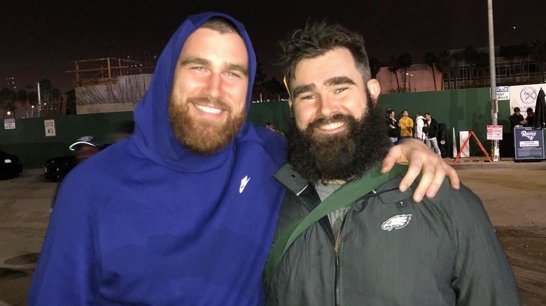 Travis Kelce smiling with arm around Jason Kelce