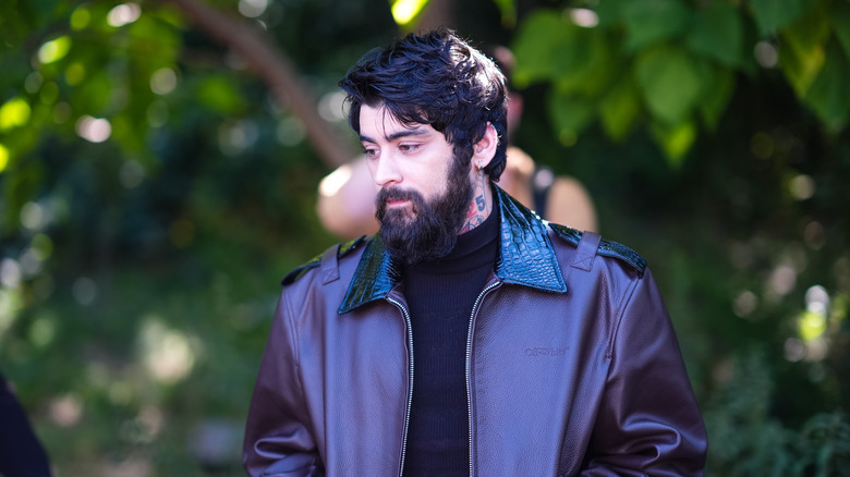 Zayn Malik with a full beard wearing a purple leather jacket