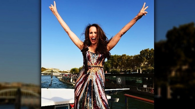 Andie MacDowell doing peace signs on boat wearing multicolor sequin dress