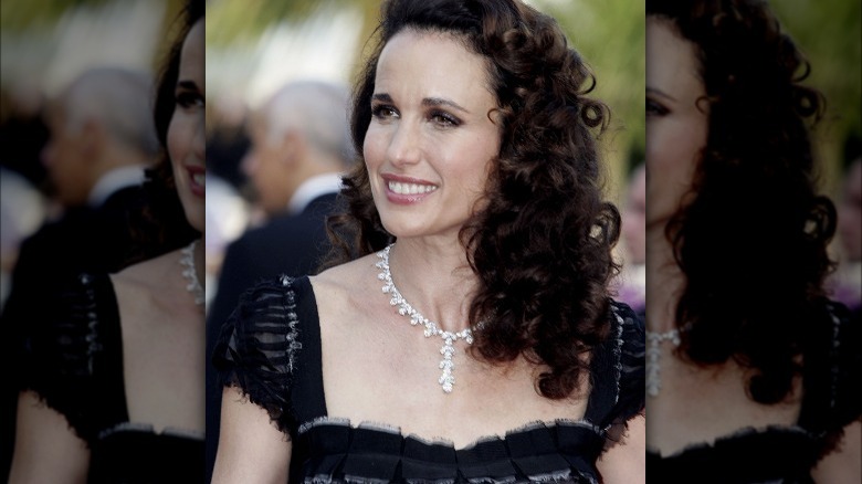 Andie MacDowell smiling in diamond necklace and chic black dress