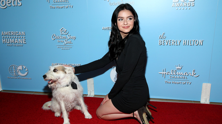 Ariel Winter petting a dog on a red carpet