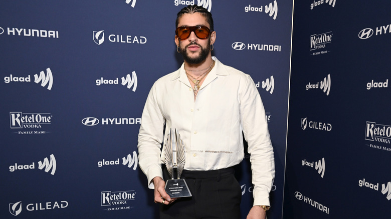 Bad Bunny holding his GLAAD Vanguard Award wearing a white dress shirt and black slacks