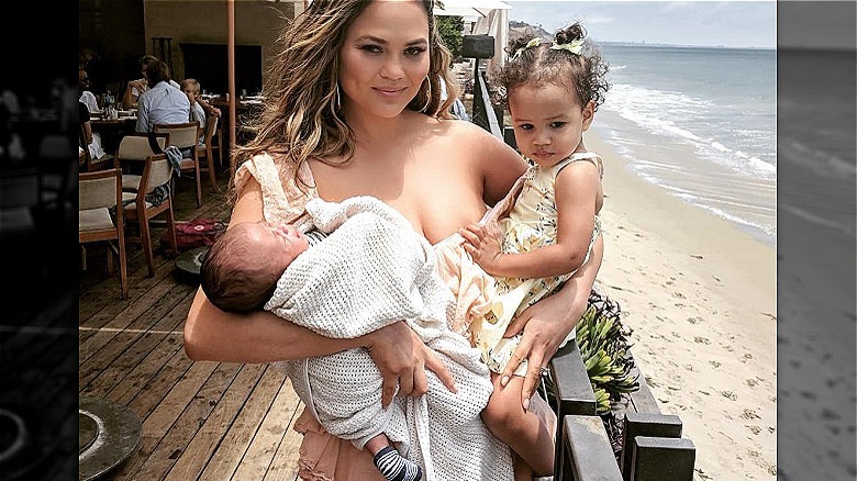 Chrissy Teigen holding Luna and Miles