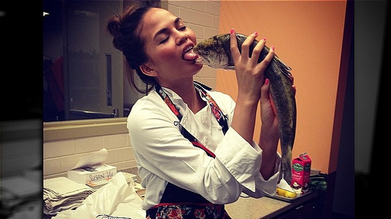 Chrissy Teigen pretending to kiss a fish