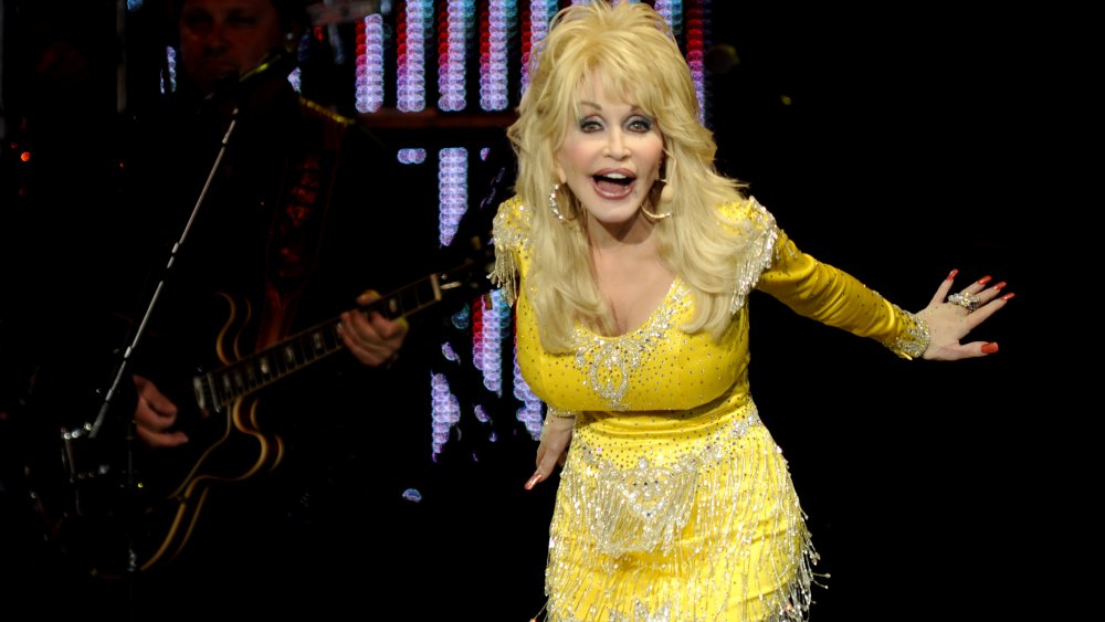 Dolly Parton in a yellow, sparkly dress, on stage in 2011 at age 65