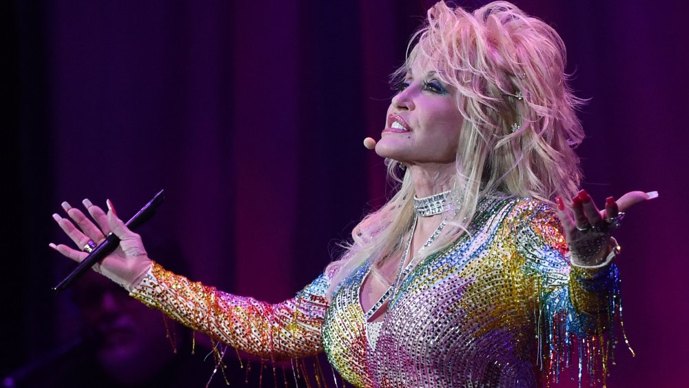 Dolly Parton singing in a rainbow-colored, sparkly dress in 2015 at age 69