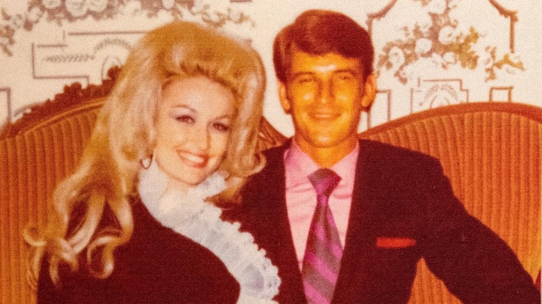 Dolly Parton and husband Carl Dean smiling and sitting on a couch