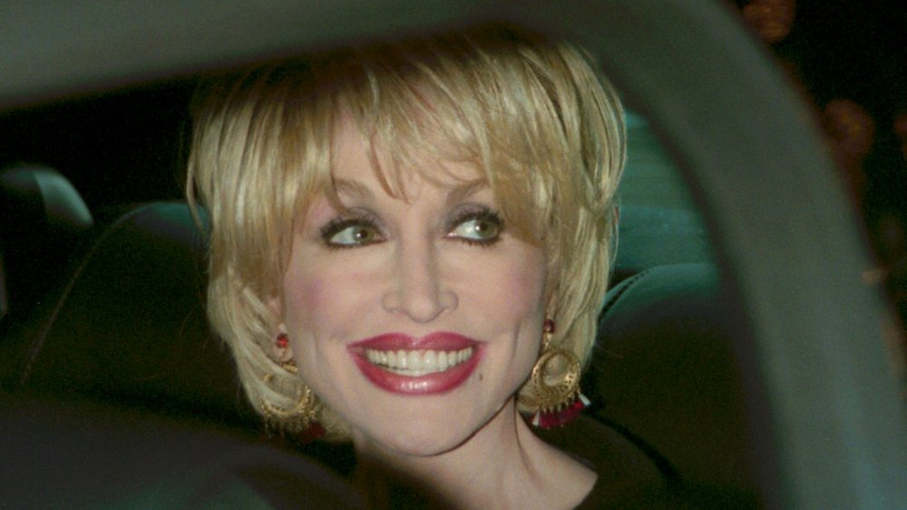 Dolly Parton smiling in a car in 2000 at age 54