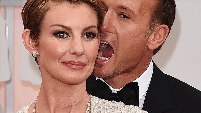 Faith Hill smiling with short hair, Tim McGraw pretending to bite her