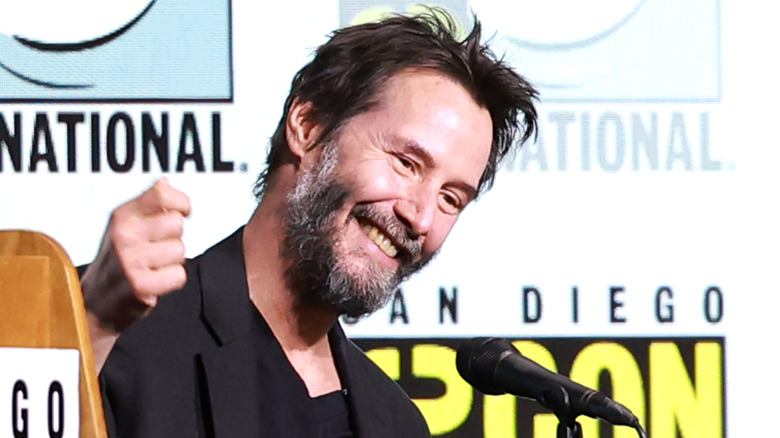 Keanu Reeves smiling during a panel at San Diego Comic-Con in 2024