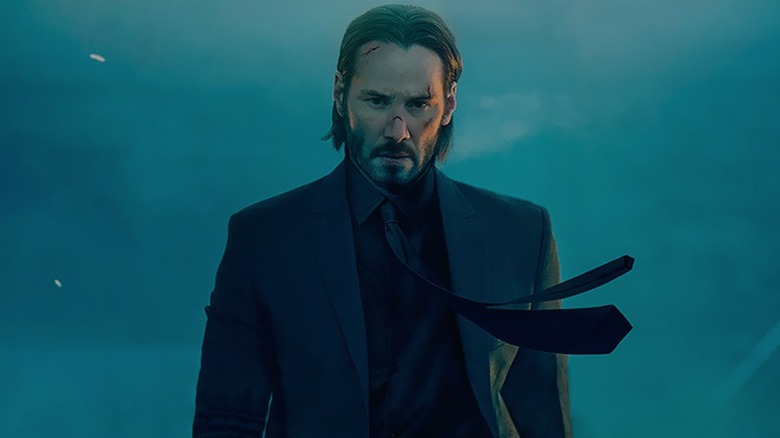 John Wick walking with determination while armed with a silenced pistol in John Wick