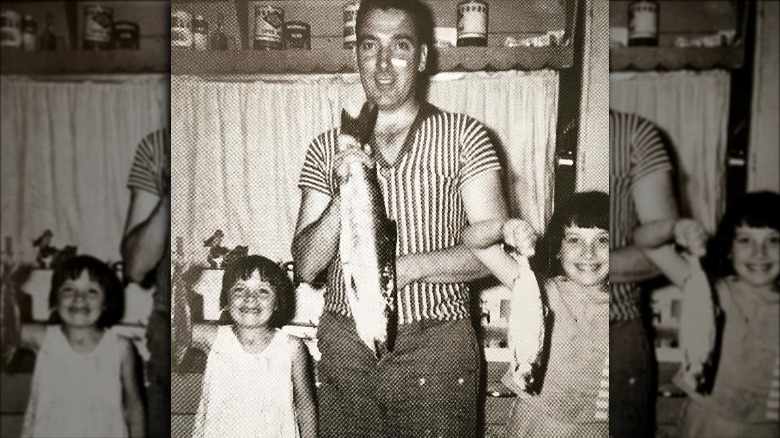 Kim Cattrall, her father, and sibling holding up fish in 1963