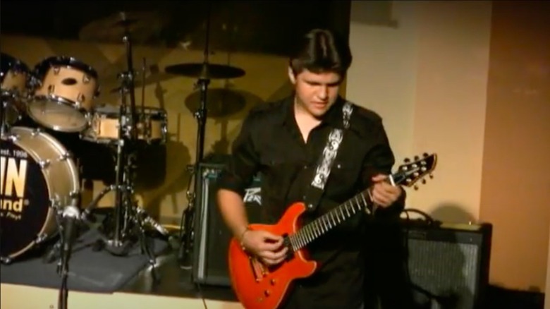 Teenage Richard Sandrak playing guitar at school concert