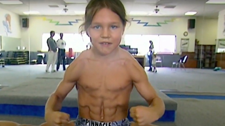 Little Hercules shows off his six-pack while posing in a gym