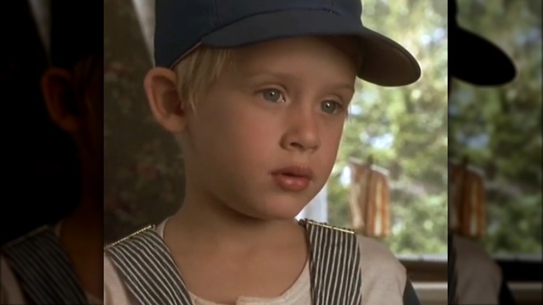 Macaulay Culkin in hat and overalls