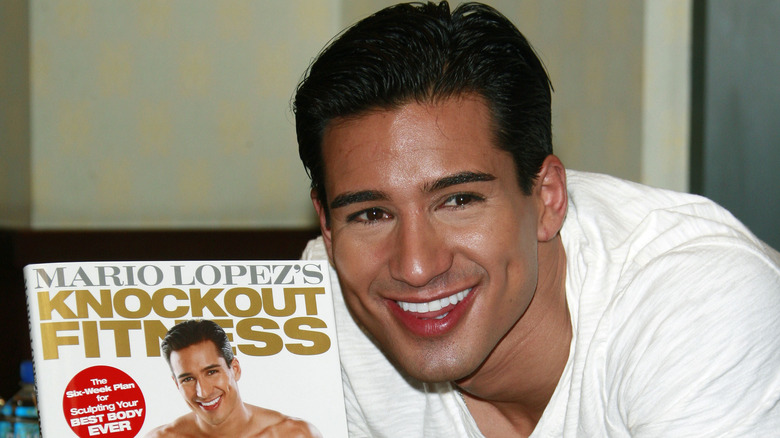 Mario Lopez smiling with his fitness book