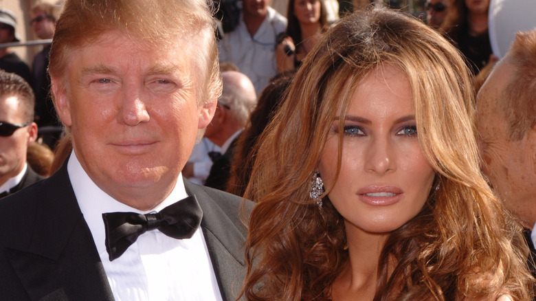 Melania Trump with wavy hair pouting next to Donald Trump