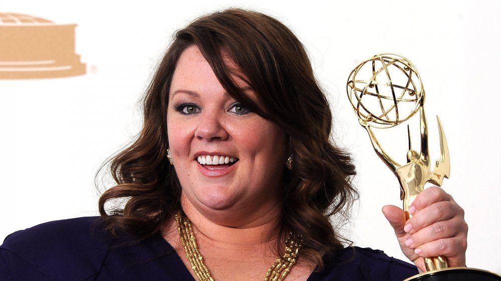 Melissa McCarthy smiling while holding her Emmy Award in 2011