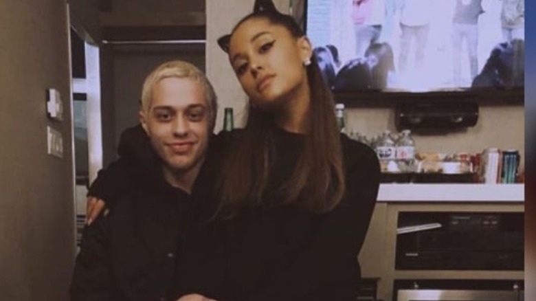 Pete Davidson and Ariana Grande sitting in his lap