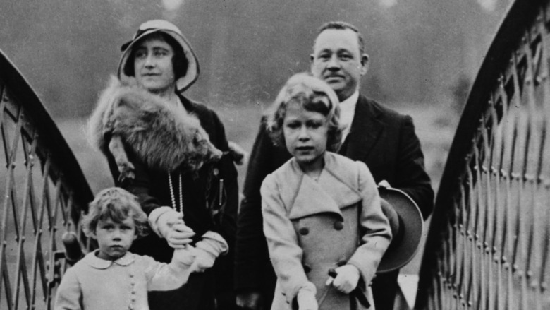 Queen Elizabeth walks a dog near her sister and mother in 1933.