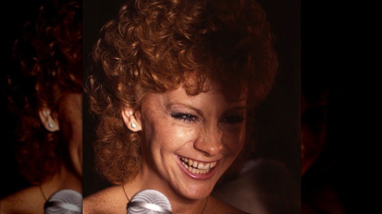 Reba Mcentire laughing in front of a mic