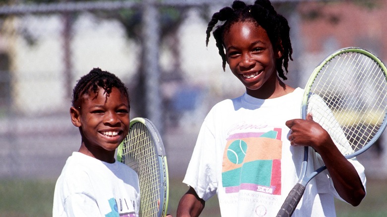 Serena Williams with big sister Venus Williams in 1991, holding rackets on a tennis court