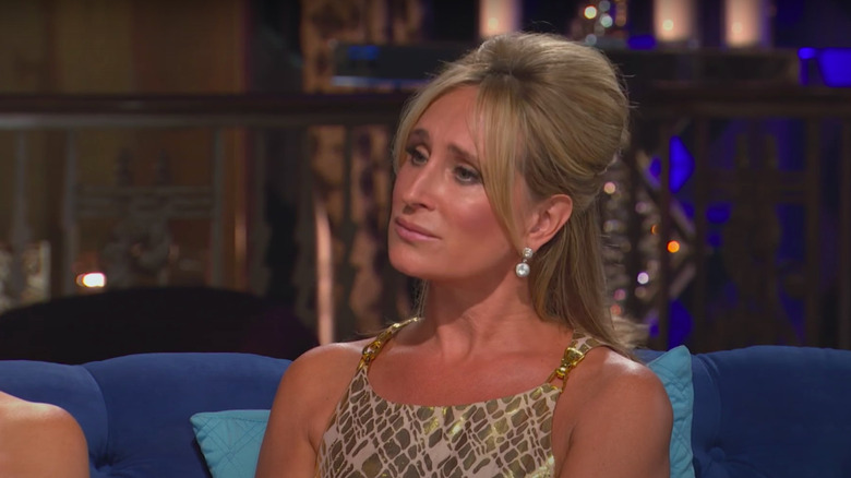 Sonja Morgan sitting on couch in full makeup and updo