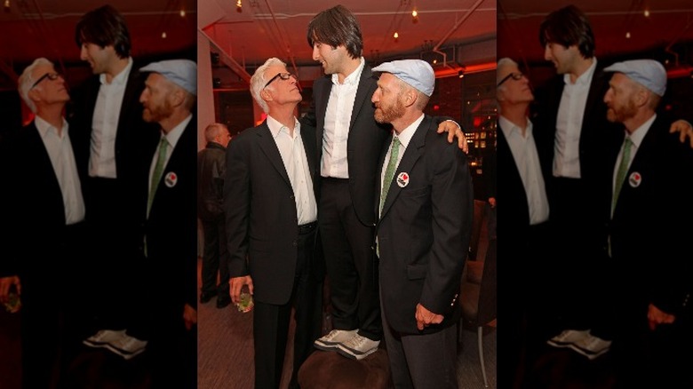 Jason Schwarzman stands on stool next to Ted Danson, Jonathan Ames