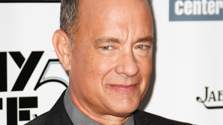 Tom Hanks posing in front of a step and repeat