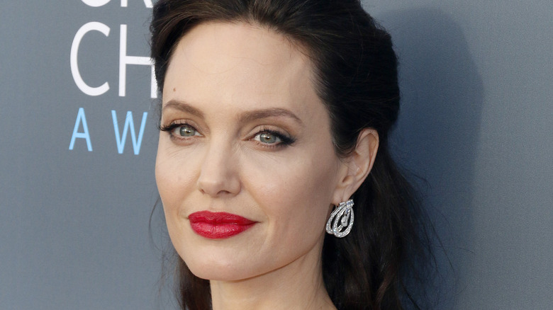 Angelina Jolie smiling in red lipstick on the red carpet