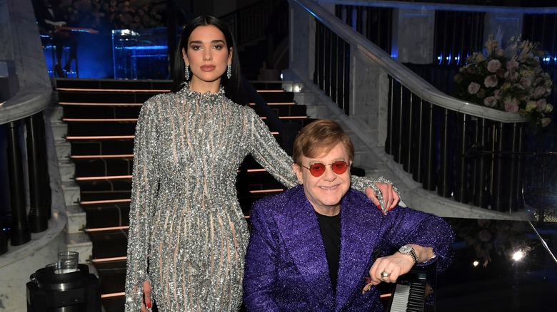 Dua Lipa standing over Elton John