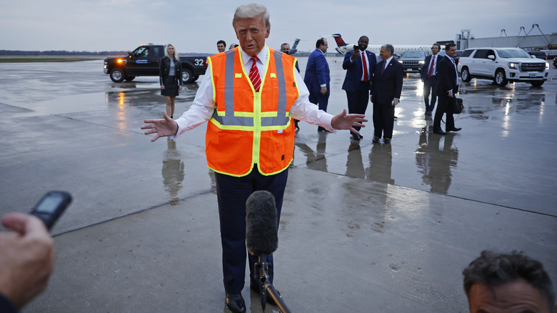 Donald Trump speaking to the press while wearing an orange safety vest