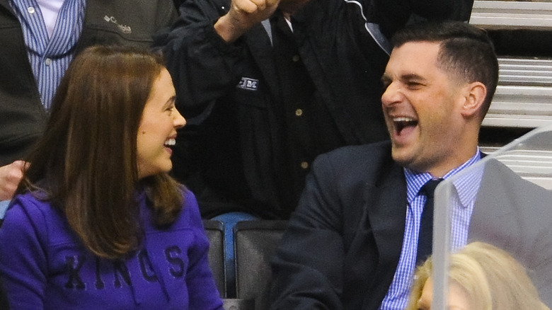 Alyssa Milano and her husband David Bugliari laughing at a basketball game