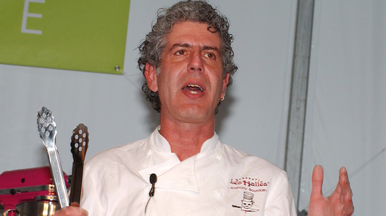 Anthony Bourdain holding tongs