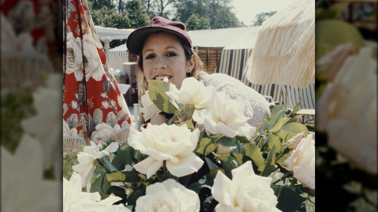 Carrie Fisher posing behind flowers