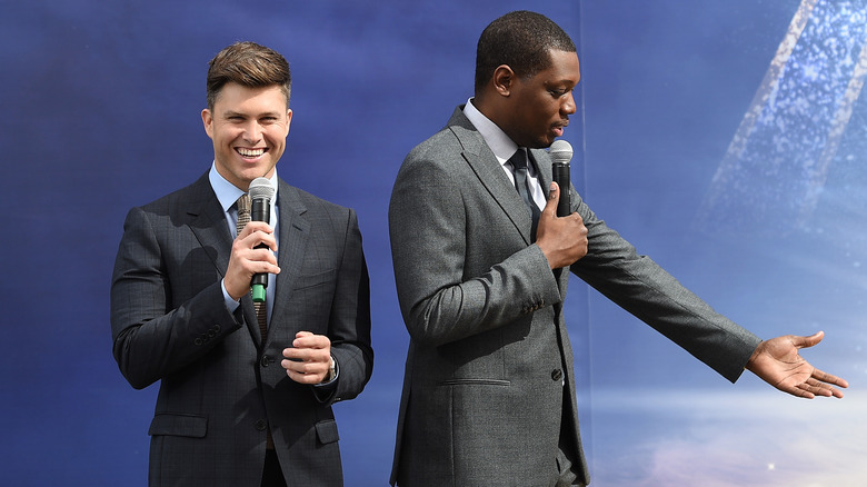 Colin Jost and Michael Che holding microphones