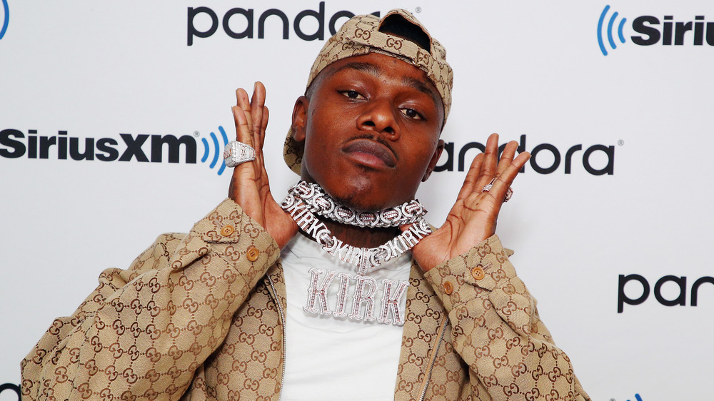 DaBaby holding up his jewelry on the red carpet