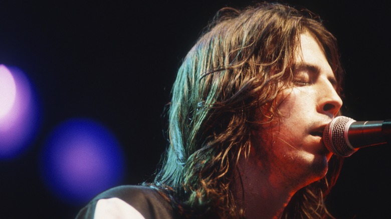 Dave Grohl singing into a microphone while performing in 1995