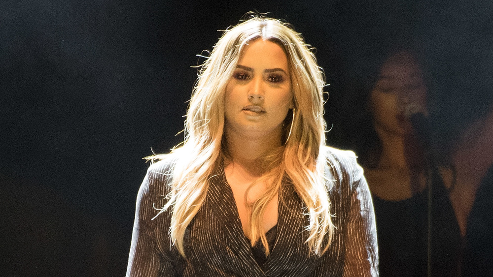 Demi Lovato standing on-stage with backup singer behind her